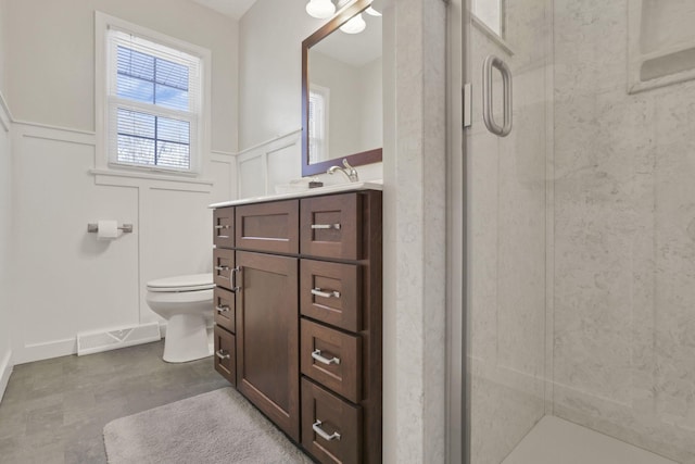 bathroom featuring vanity, a shower with door, and toilet