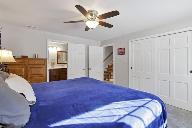 bedroom with connected bathroom, light colored carpet, ceiling fan, and a closet