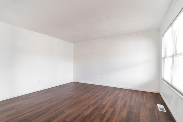 spare room featuring ornamental molding and dark hardwood / wood-style floors