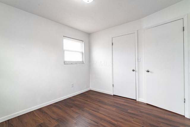 unfurnished bedroom with dark wood-type flooring