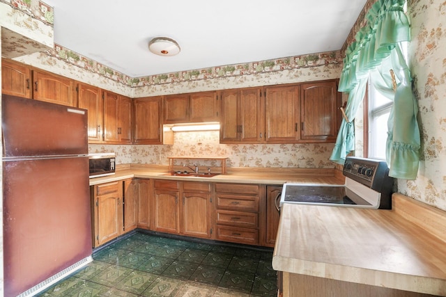 kitchen featuring fridge, sink, and electric range