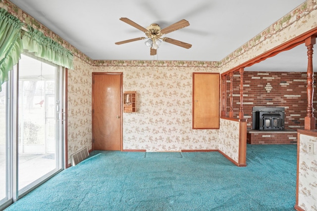 unfurnished living room featuring carpet, ceiling fan, and a wood stove