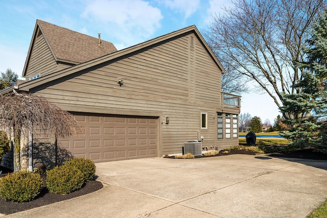 view of home's exterior with central AC unit, a garage, and a balcony