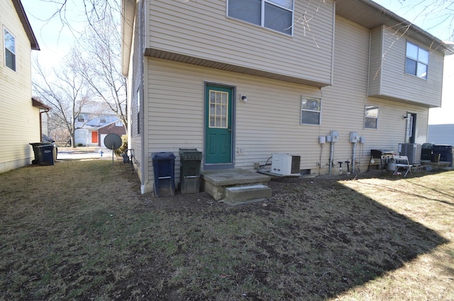 rear view of property featuring cooling unit and a lawn