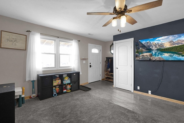 playroom with ceiling fan and dark colored carpet