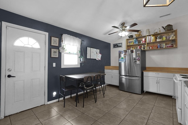 kitchen featuring stainless steel fridge, ceiling fan, white range with electric stovetop, white cabinets, and light tile patterned flooring