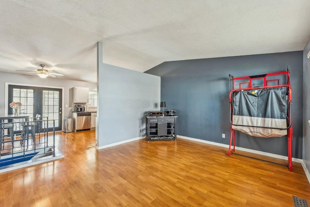 interior space with ceiling fan, vaulted ceiling, a textured ceiling, and light wood-type flooring