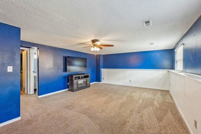 unfurnished living room with ceiling fan, carpet floors, and a textured ceiling