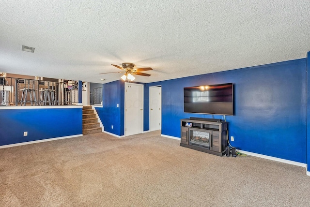 unfurnished living room with ceiling fan, carpet, and a textured ceiling