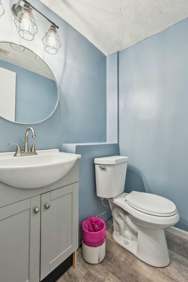 bathroom with vanity, hardwood / wood-style floors, a textured ceiling, and toilet