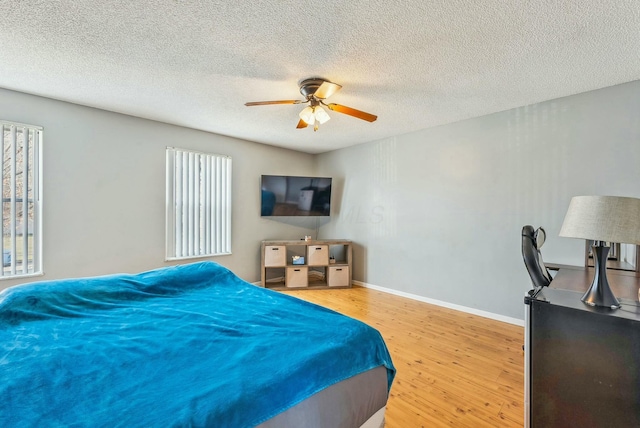 bedroom with multiple windows, hardwood / wood-style floors, a textured ceiling, and ceiling fan