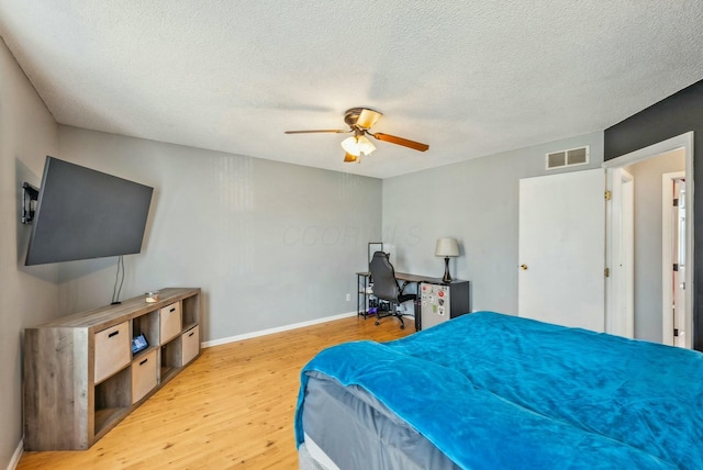 bedroom with ceiling fan, a textured ceiling, and light wood-type flooring