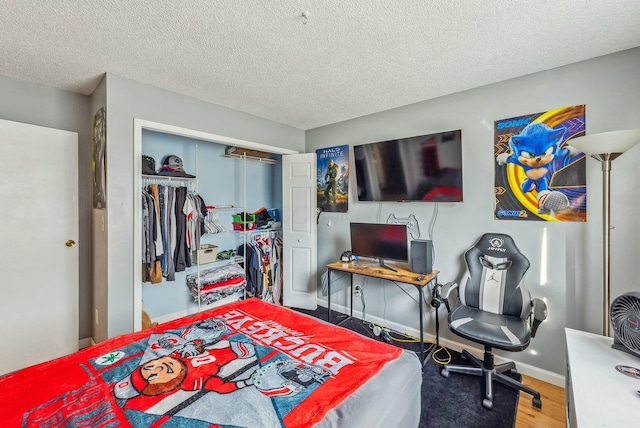 bedroom with hardwood / wood-style floors, a textured ceiling, and a closet