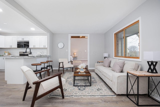 living area featuring baseboards and light wood finished floors