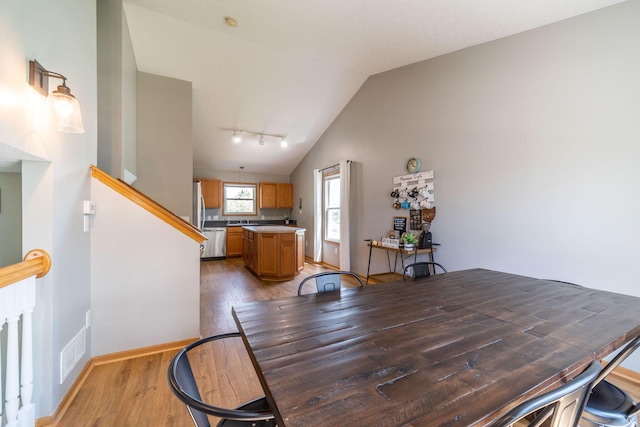 dining room featuring lofted ceiling, sink, and wood-type flooring