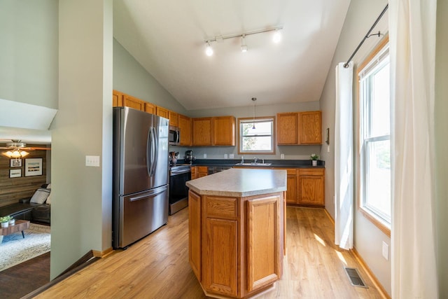 kitchen with appliances with stainless steel finishes, pendant lighting, lofted ceiling, sink, and a center island