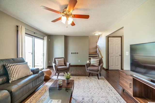 living room featuring ceiling fan, dark hardwood / wood-style floors, and a textured ceiling