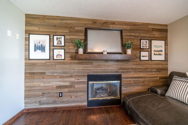 unfurnished living room featuring wood-type flooring, a textured ceiling, and wood walls