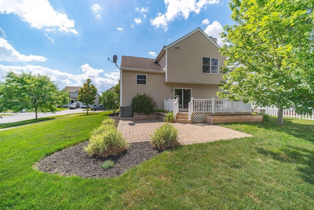 rear view of property featuring central AC unit, a patio, and a lawn