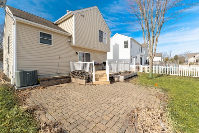 rear view of property featuring cooling unit, a yard, a wooden deck, and a patio