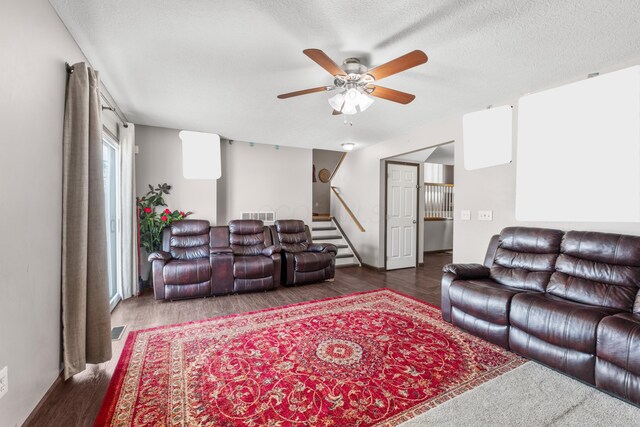 living room with dark hardwood / wood-style flooring, ceiling fan, and a textured ceiling