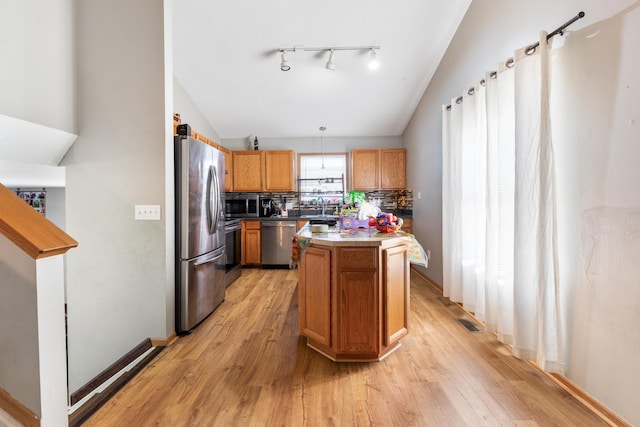 kitchen featuring stainless steel appliances, a kitchen island, light hardwood / wood-style floors, and decorative light fixtures