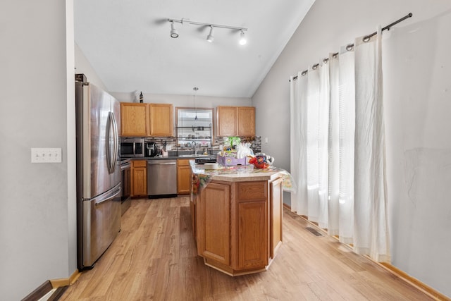 kitchen featuring stainless steel appliances, sink, pendant lighting, and light wood-type flooring