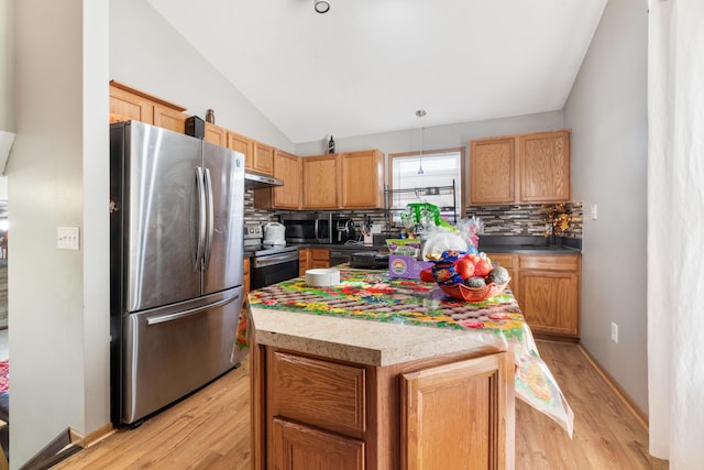 kitchen with vaulted ceiling, a kitchen island, pendant lighting, stainless steel appliances, and light hardwood / wood-style floors