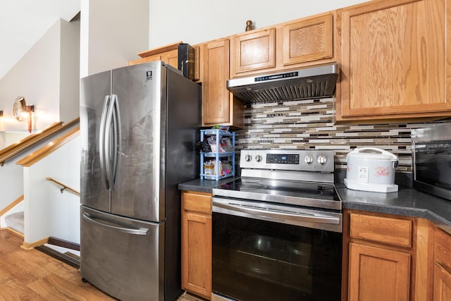 kitchen featuring backsplash, stainless steel appliances, light hardwood / wood-style flooring, and exhaust hood