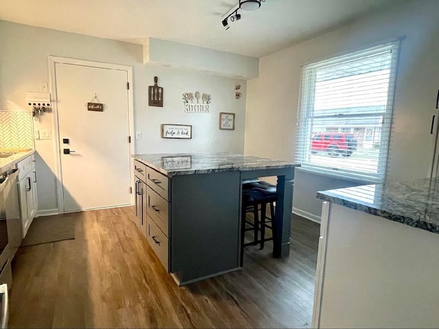 kitchen with stone counters, a kitchen breakfast bar, dark hardwood / wood-style floors, tasteful backsplash, and a kitchen island