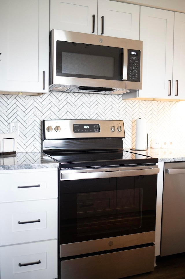 kitchen with white cabinetry, appliances with stainless steel finishes, light stone counters, and decorative backsplash