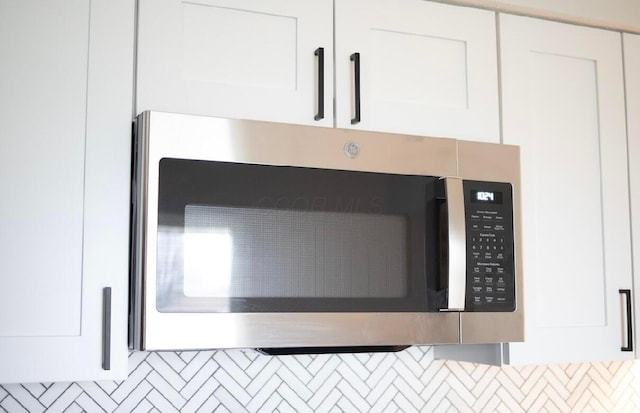 interior details with decorative backsplash and white cabinets