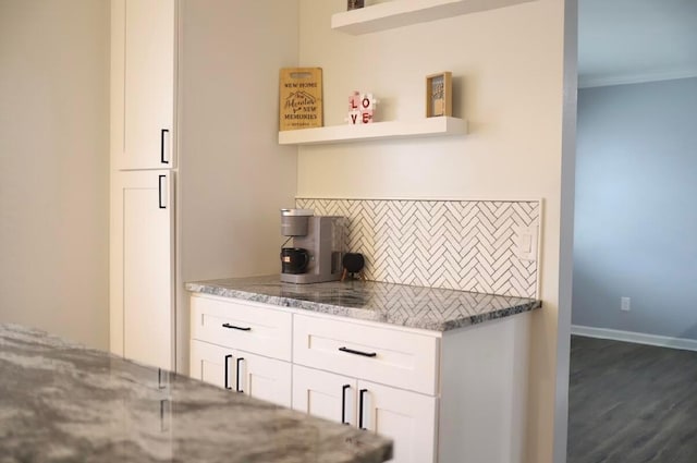 kitchen featuring dark wood-type flooring, white cabinetry, light stone counters, ornamental molding, and decorative backsplash