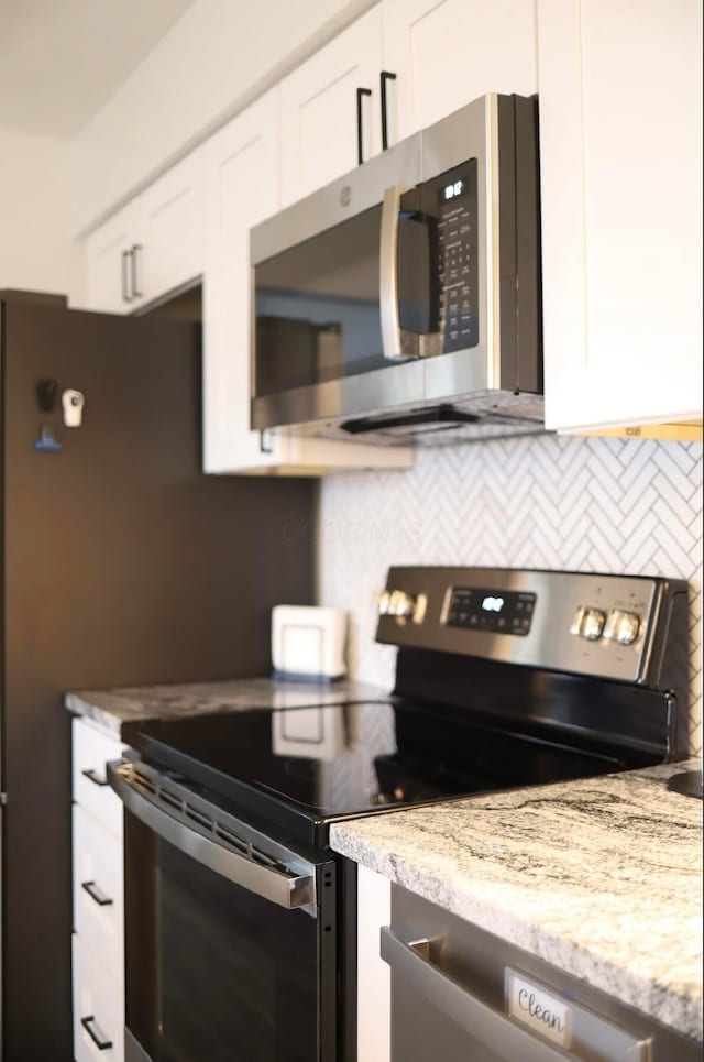 kitchen featuring white cabinetry, appliances with stainless steel finishes, and light stone counters