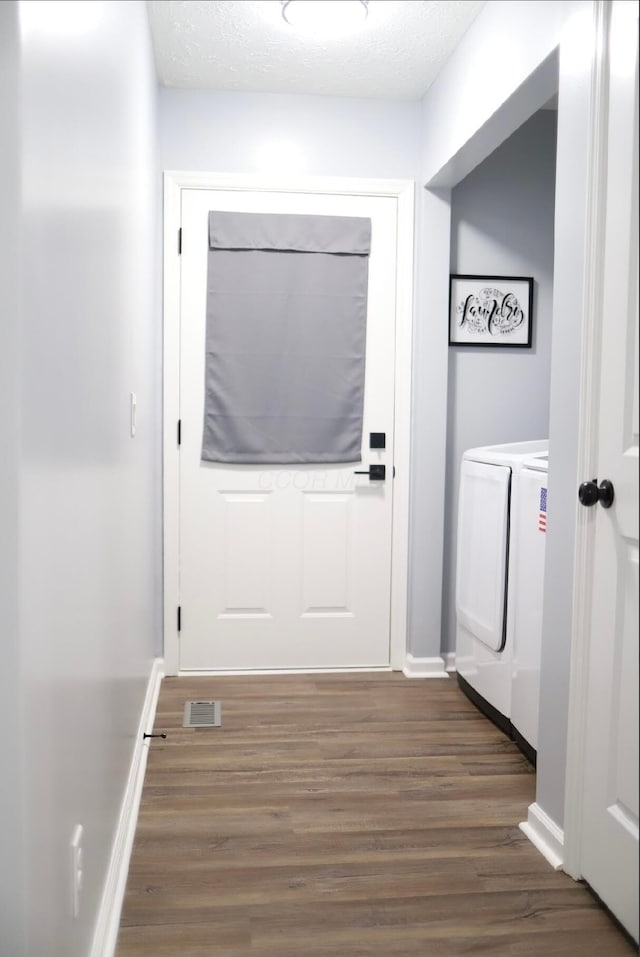 entryway with dark hardwood / wood-style flooring, a textured ceiling, and independent washer and dryer