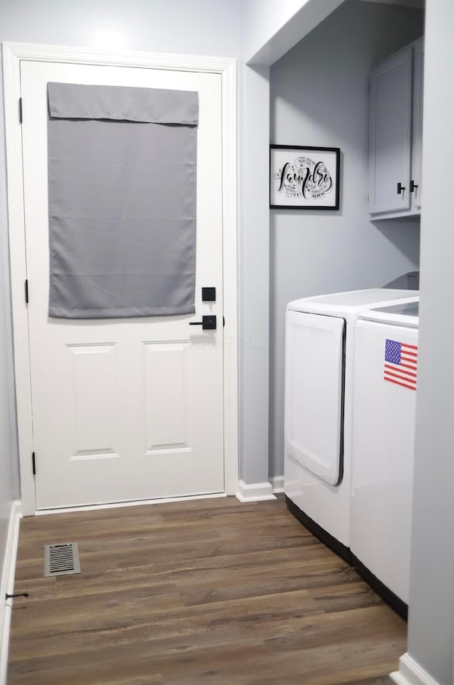 clothes washing area with cabinets, dark wood-type flooring, and washer and clothes dryer