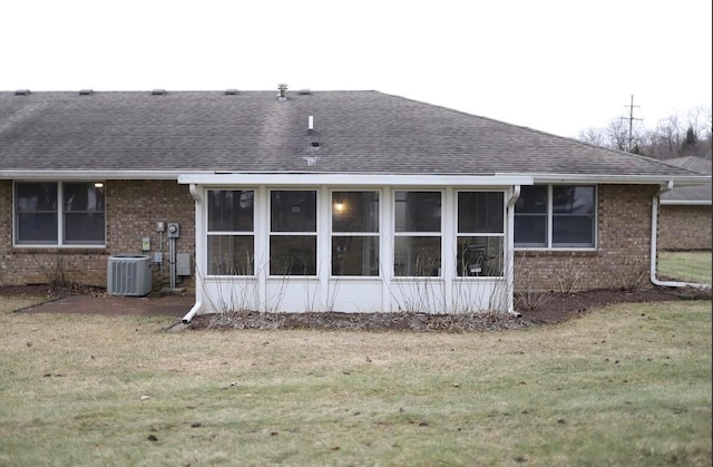 back of property with central AC unit, a lawn, and a sunroom