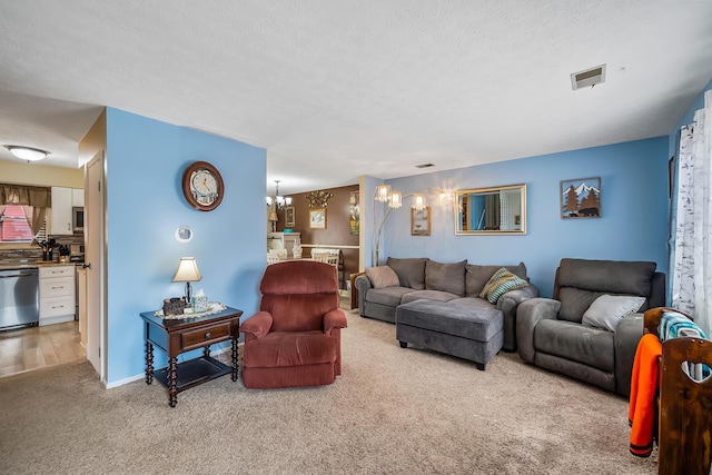 carpeted living area featuring an inviting chandelier, baseboards, visible vents, and a textured ceiling