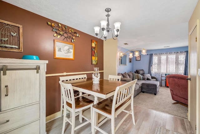 dining area with wood finished floors and an inviting chandelier