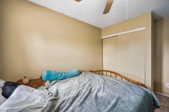 carpeted bedroom featuring a textured ceiling, a closet, and a ceiling fan