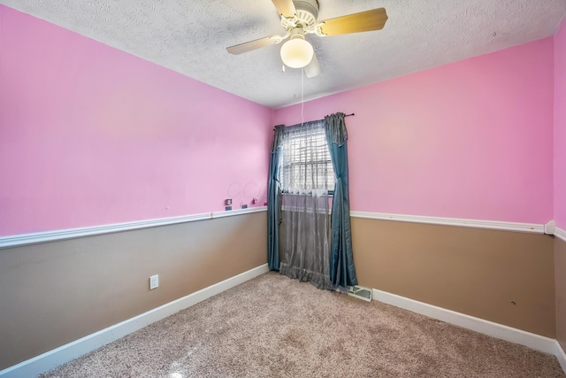 spare room featuring a textured ceiling, carpet floors, a ceiling fan, and baseboards