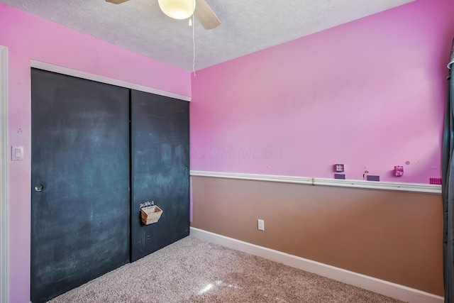 unfurnished bedroom featuring baseboards, ceiling fan, carpet, a textured ceiling, and a closet