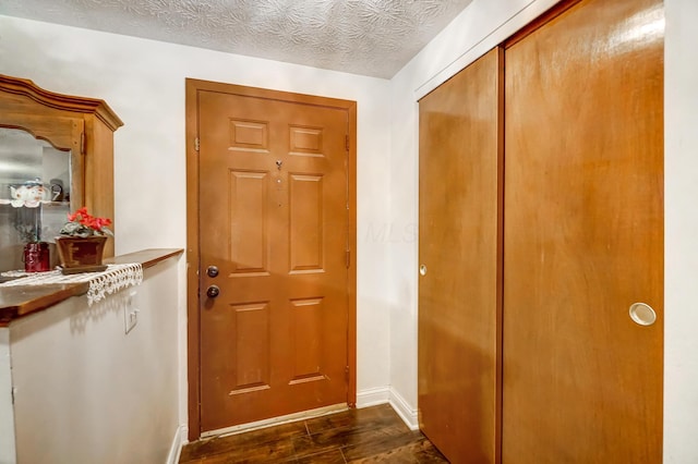 doorway to outside with dark wood-type flooring and a textured ceiling