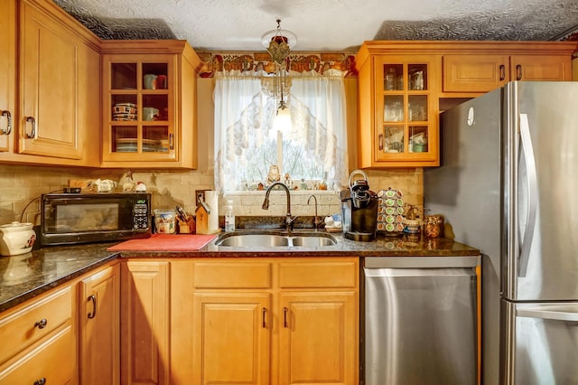 kitchen with sink, hanging light fixtures, appliances with stainless steel finishes, dark stone counters, and backsplash