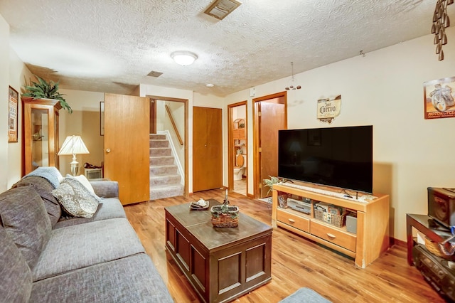 living room with a textured ceiling and light wood-type flooring