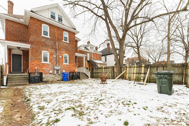 snow covered back of property featuring central air condition unit