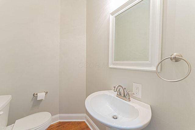 bathroom with toilet, sink, and hardwood / wood-style floors