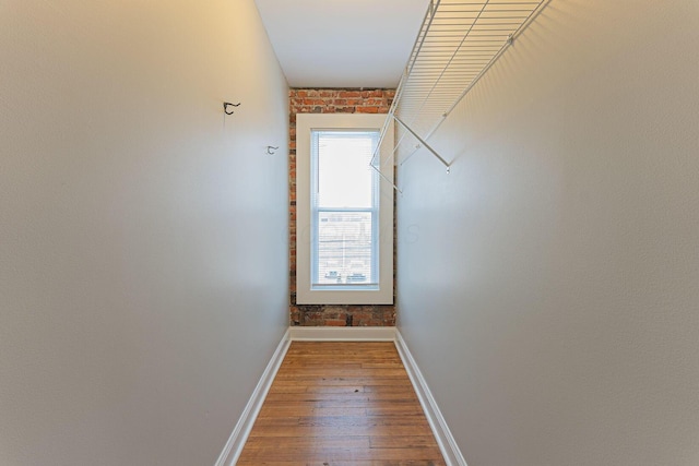 hall featuring brick wall and hardwood / wood-style floors