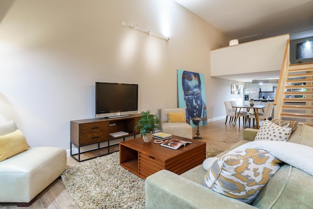 living room with a towering ceiling and light hardwood / wood-style flooring