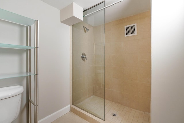 bathroom with a tile shower and toilet